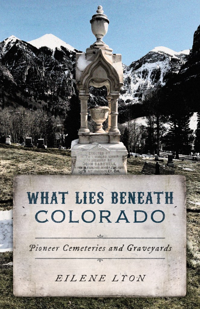 Book cover for What Lies Beneath Colorado Pioneer Cemeteries and Graveyards. Lone Tree Cemetery in Telluride, Colorado, with snowy mountains in the background.